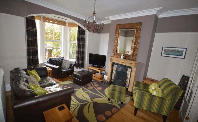 Living room with a large TV. There are two arm chairs and one long sofa